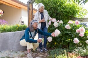 Two women admire pink flowers in a garden.